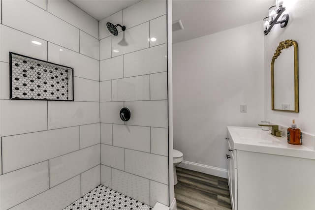 bathroom featuring tiled shower, hardwood / wood-style floors, vanity, and toilet