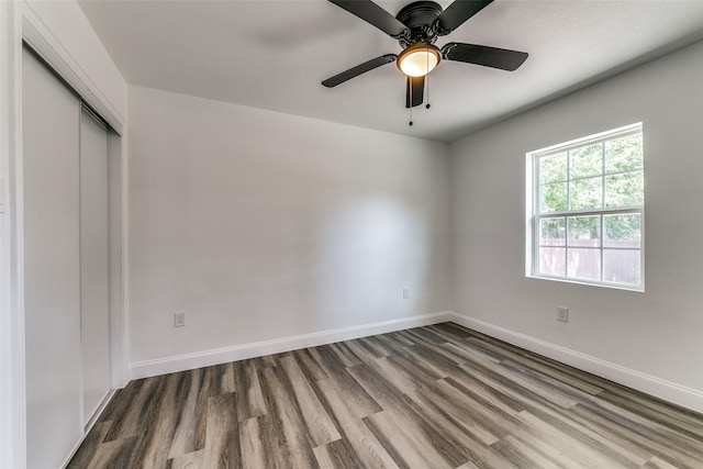 unfurnished bedroom with ceiling fan, a closet, and hardwood / wood-style flooring