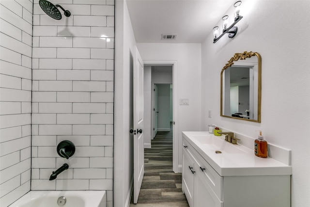 bathroom with tiled shower / bath combo, wood-type flooring, and vanity