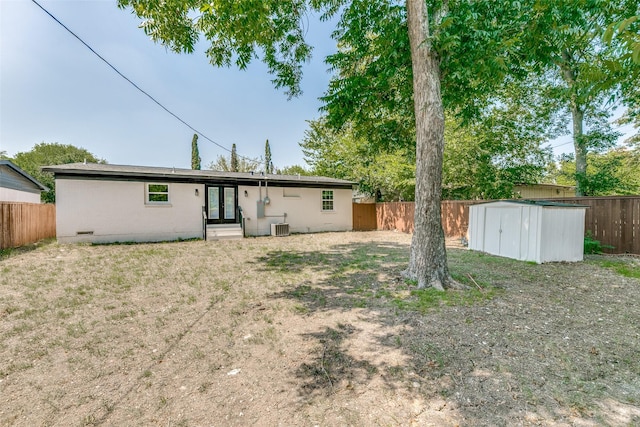 rear view of house with central air condition unit, french doors, and a shed