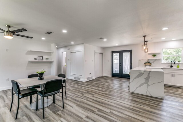 dining room featuring ceiling fan, french doors, sink, and light wood-type flooring