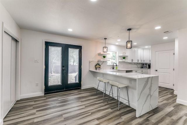 kitchen featuring kitchen peninsula, tasteful backsplash, sink, decorative light fixtures, and white cabinets