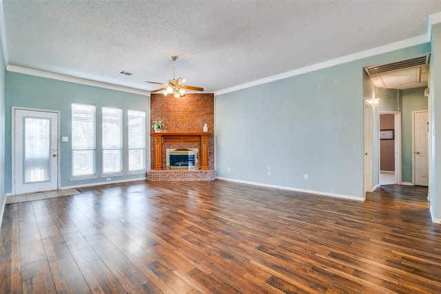 unfurnished living room featuring dark wood-type flooring, a brick fireplace, ceiling fan, ornamental molding, and a textured ceiling