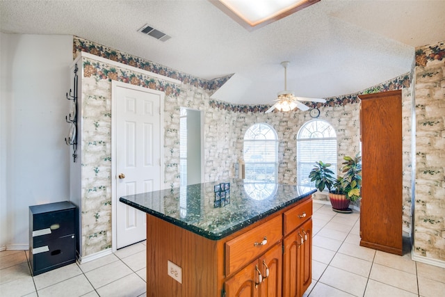 kitchen featuring ceiling fan, a center island, light tile patterned floors, and a textured ceiling