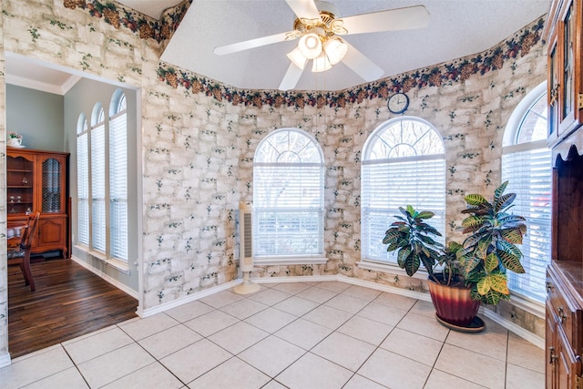 interior space featuring ceiling fan, crown molding, and light tile patterned floors