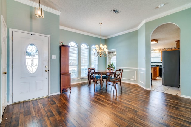 foyer entrance featuring crown molding, plenty of natural light, wood-type flooring, and a textured ceiling