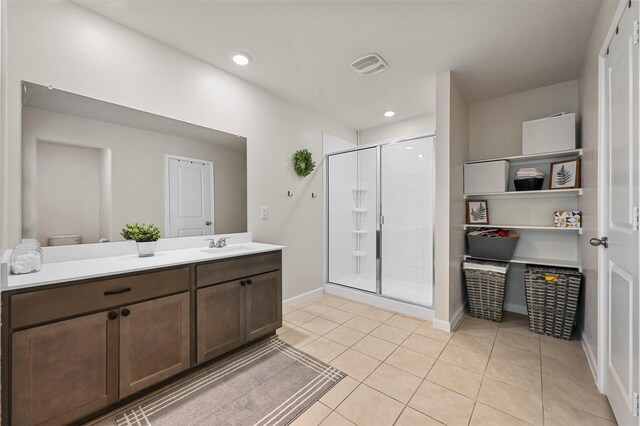 bathroom featuring toilet, vanity, tile patterned floors, and a shower with door