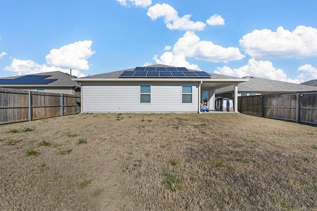 rear view of house featuring solar panels, a carport, and a lawn