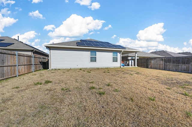 back of property with a yard and solar panels