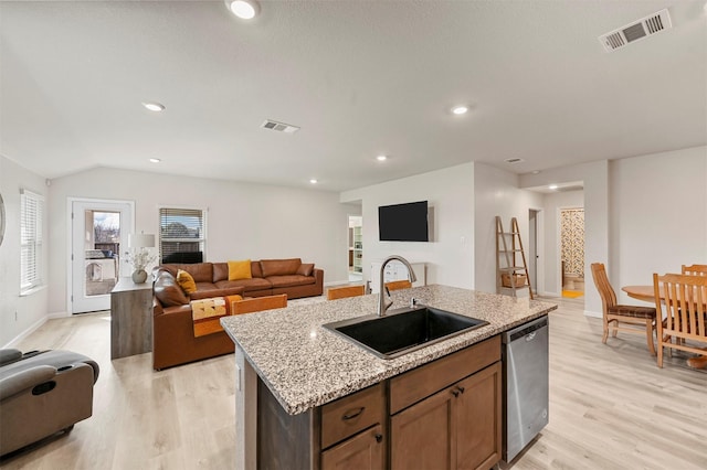 kitchen featuring stainless steel dishwasher, light hardwood / wood-style floors, sink, and an island with sink