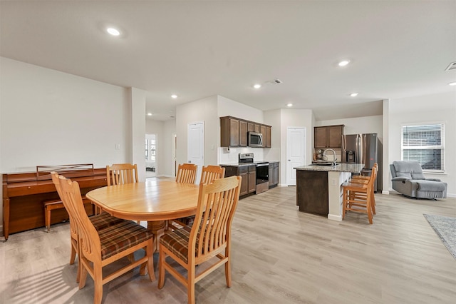 dining space featuring light hardwood / wood-style flooring, a healthy amount of sunlight, and sink