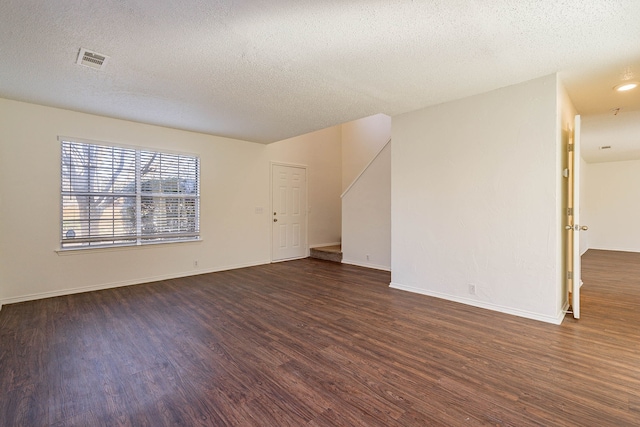 empty room with dark wood-type flooring and a textured ceiling