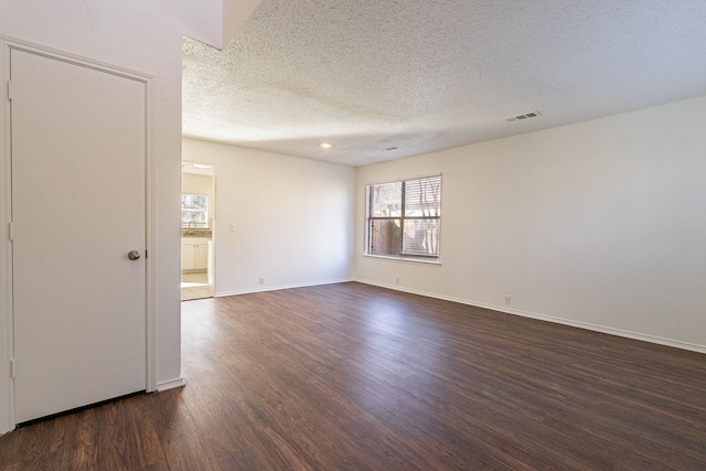 unfurnished room with dark wood-type flooring and a textured ceiling