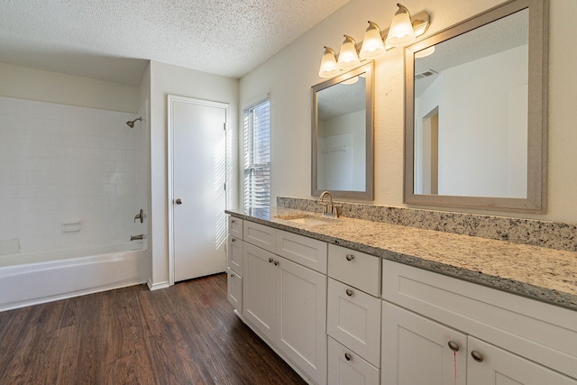 bathroom with vanity, tiled shower / bath combo, wood-type flooring, and a textured ceiling