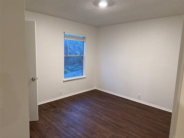 empty room with dark hardwood / wood-style flooring and a textured ceiling