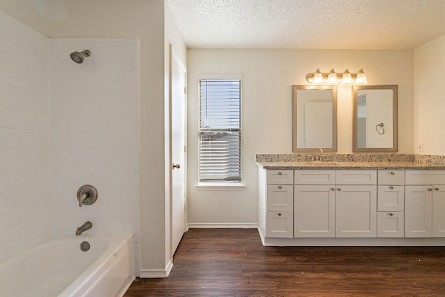 bathroom featuring vanity, tiled shower / bath combo, hardwood / wood-style floors, and a textured ceiling