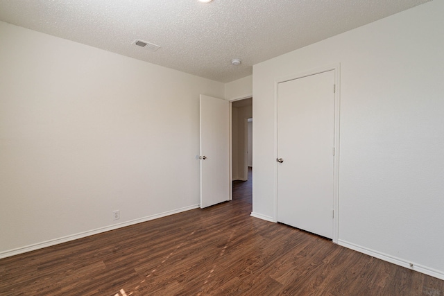 unfurnished room featuring dark hardwood / wood-style flooring and a textured ceiling