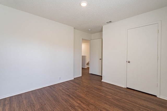 unfurnished bedroom featuring dark wood-type flooring and a textured ceiling