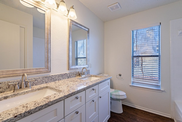 bathroom featuring vanity, toilet, hardwood / wood-style floors, and a textured ceiling