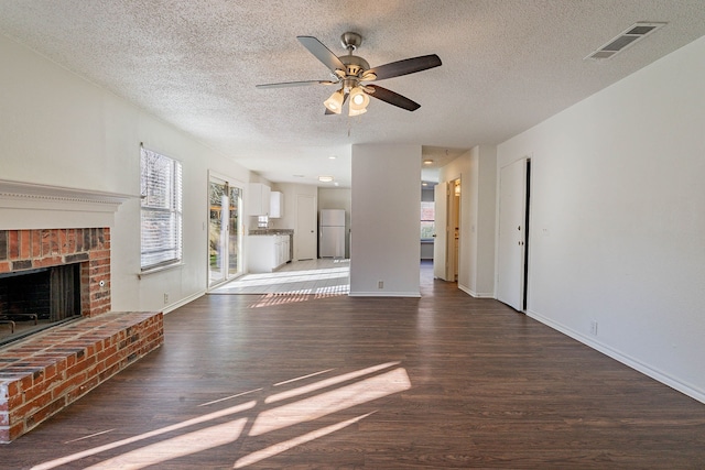 unfurnished living room with dark hardwood / wood-style floors, ceiling fan, a fireplace, and a wealth of natural light