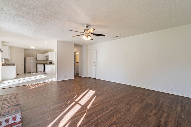 unfurnished living room with sink, a textured ceiling, dark hardwood / wood-style floors, and ceiling fan