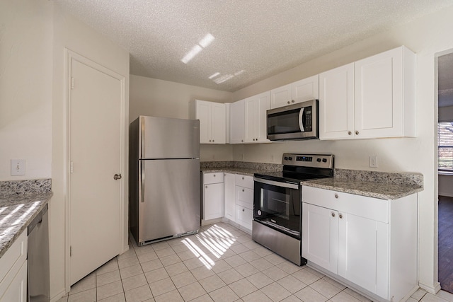 kitchen featuring white cabinetry, light tile patterned floors, stainless steel appliances, and a textured ceiling