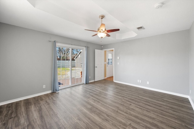 spare room featuring dark hardwood / wood-style flooring, a tray ceiling, and ceiling fan