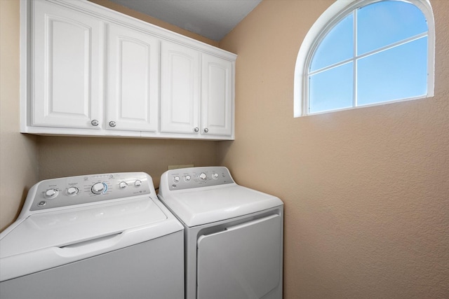 clothes washing area with cabinets and washer and clothes dryer