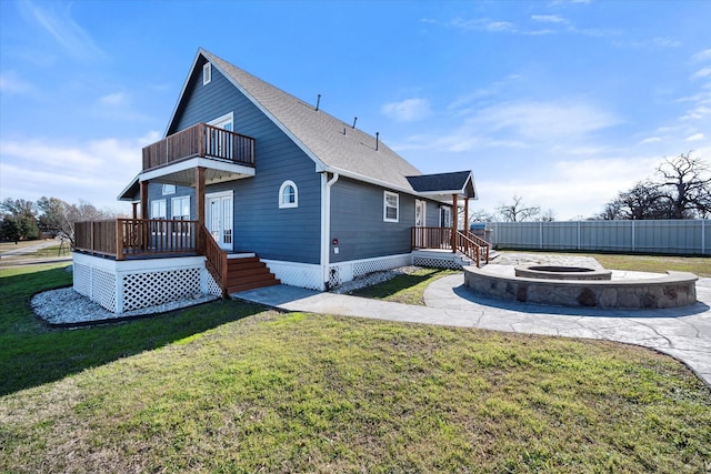 rear view of house featuring a yard, an outdoor fire pit, and a balcony