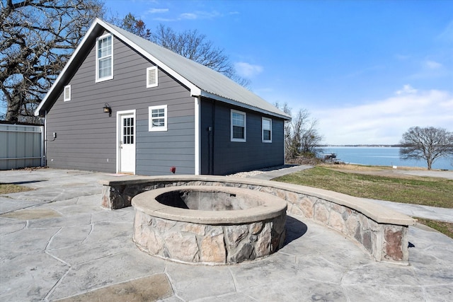 rear view of house with a patio, a water view, and a fire pit