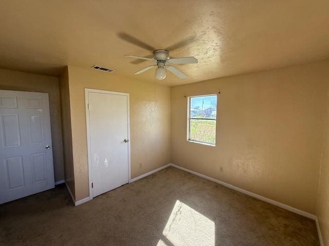 unfurnished bedroom with ceiling fan and dark carpet