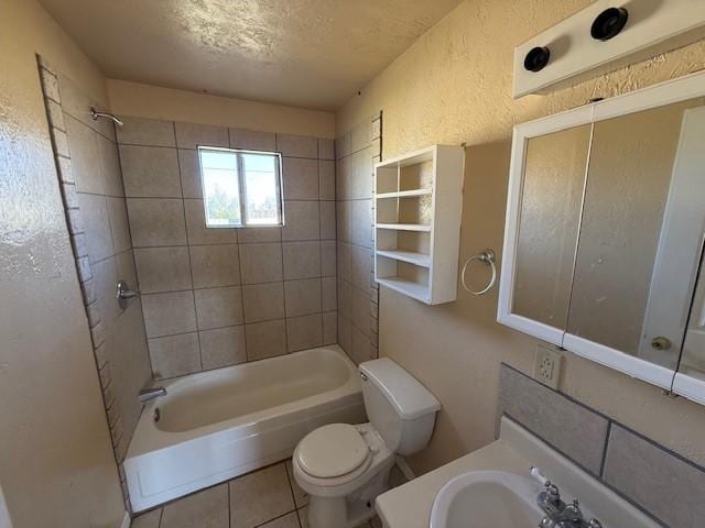 full bathroom featuring sink, tile patterned flooring, a textured ceiling, toilet, and tiled shower / bath