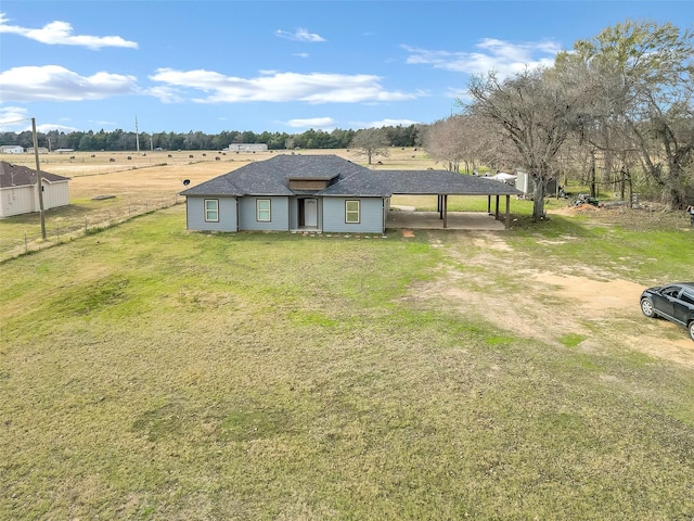 ranch-style home with a carport, a rural view, and a front lawn