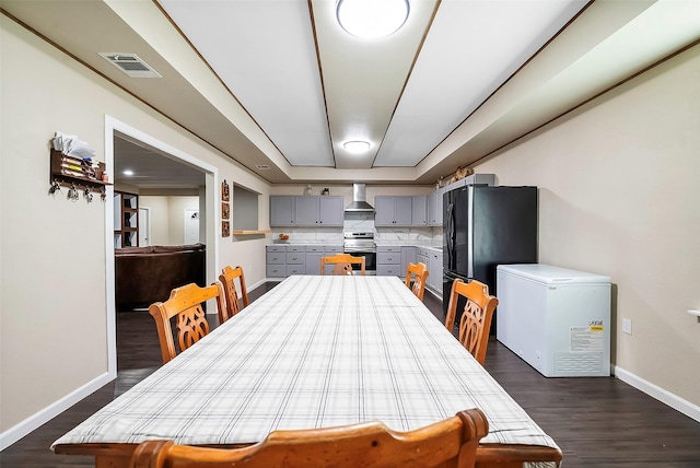 dining area with dark wood-type flooring and a raised ceiling