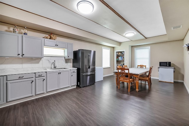 kitchen with stainless steel refrigerator, sink, dark hardwood / wood-style floors, gray cabinets, and decorative backsplash