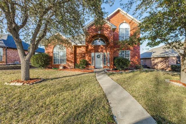 traditional-style home with brick siding and a front lawn