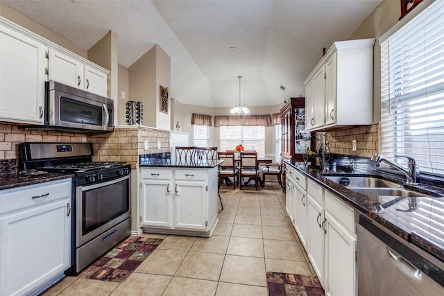 kitchen featuring white cabinetry, sink, vaulted ceiling, and appliances with stainless steel finishes