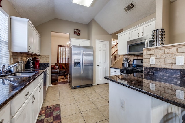 kitchen featuring decorative backsplash, stainless steel appliances, white cabinetry, and lofted ceiling