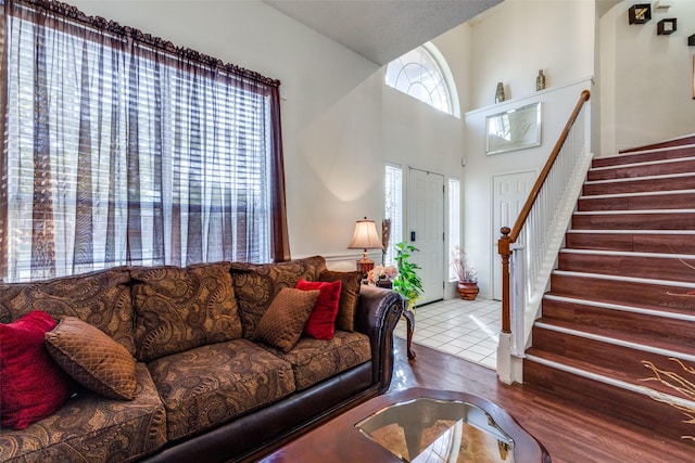 living area with stairs, wood finished floors, and a towering ceiling