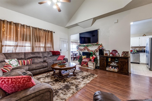 living room featuring ceiling fan, light hardwood / wood-style floors, and vaulted ceiling