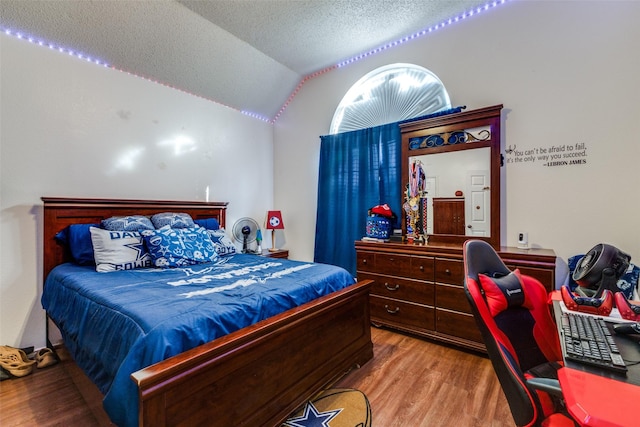 bedroom with light hardwood / wood-style floors, a textured ceiling, and vaulted ceiling