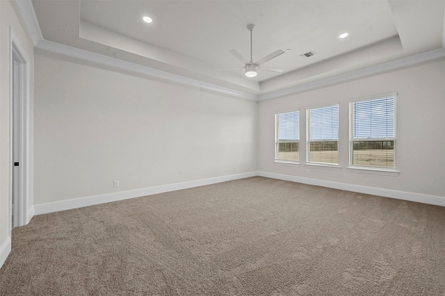 carpeted spare room featuring ceiling fan and a tray ceiling