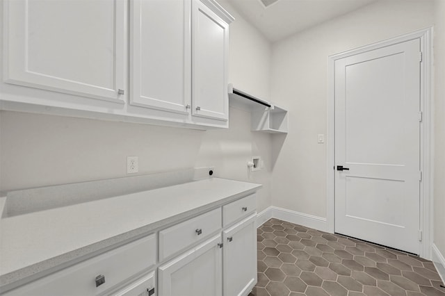 laundry area with hookup for a washing machine, hookup for an electric dryer, dark tile patterned flooring, and cabinets