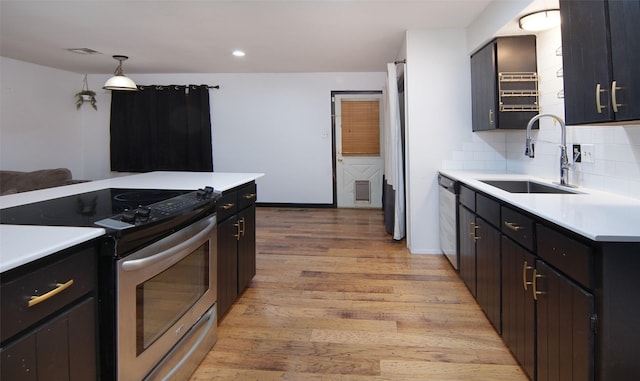 kitchen featuring appliances with stainless steel finishes, pendant lighting, sink, decorative backsplash, and light hardwood / wood-style floors