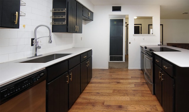 kitchen featuring stainless steel appliances, sink, backsplash, and light hardwood / wood-style flooring