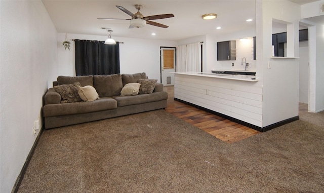 living room with sink, dark carpet, and ceiling fan