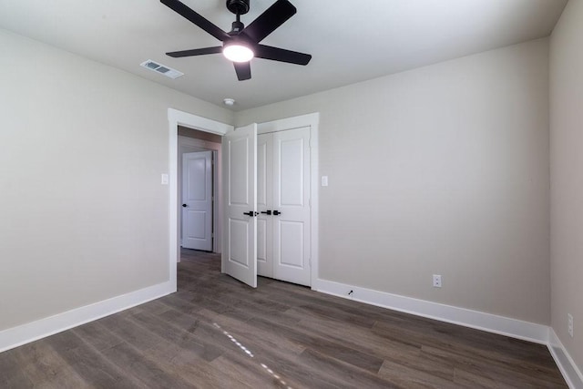 unfurnished bedroom featuring a closet, dark hardwood / wood-style floors, and ceiling fan