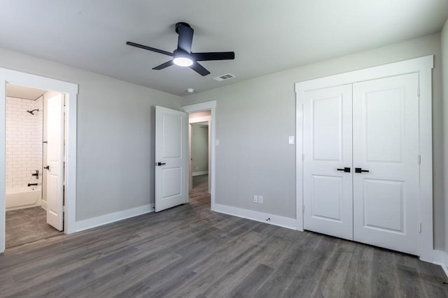 unfurnished bedroom with connected bathroom, a closet, ceiling fan, and dark wood-type flooring