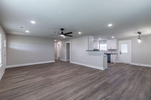 unfurnished living room featuring ceiling fan and dark wood-type flooring