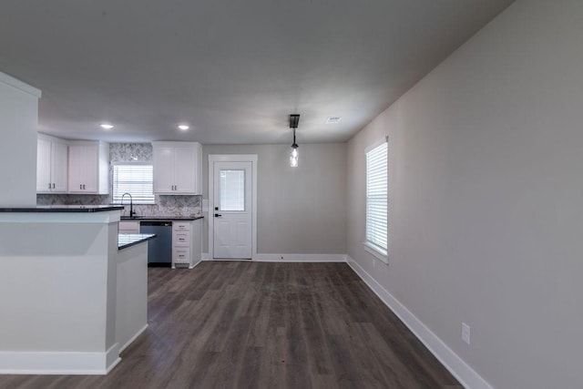 kitchen with backsplash, dark wood-type flooring, dishwasher, white cabinetry, and hanging light fixtures